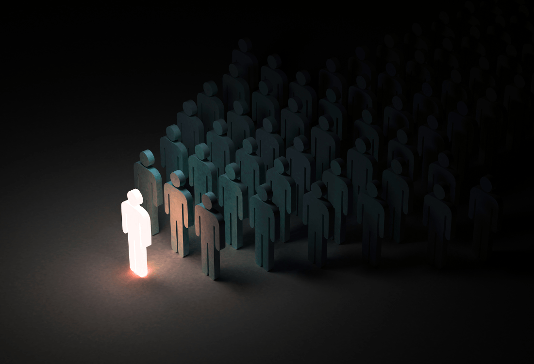 Leadership concept showing illuminated figure standing out from crowd, representing developing leadership capability through mindset transformation and authentic leadership identity.